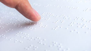 Image shows person reading braille