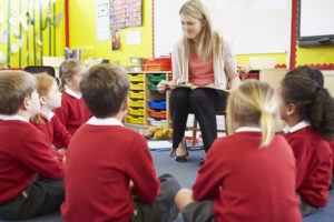 Revamp Of Primary Assessment: Image shows teacher reading to children