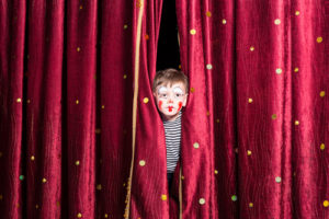 Theatre in education: Image shows child looking through theatre curtains