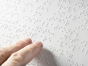 A braille page with a person using two fingers to read it.